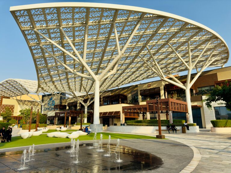 Stunning outdoor plaza with architectural canopy, water fountains, and seating areas.
