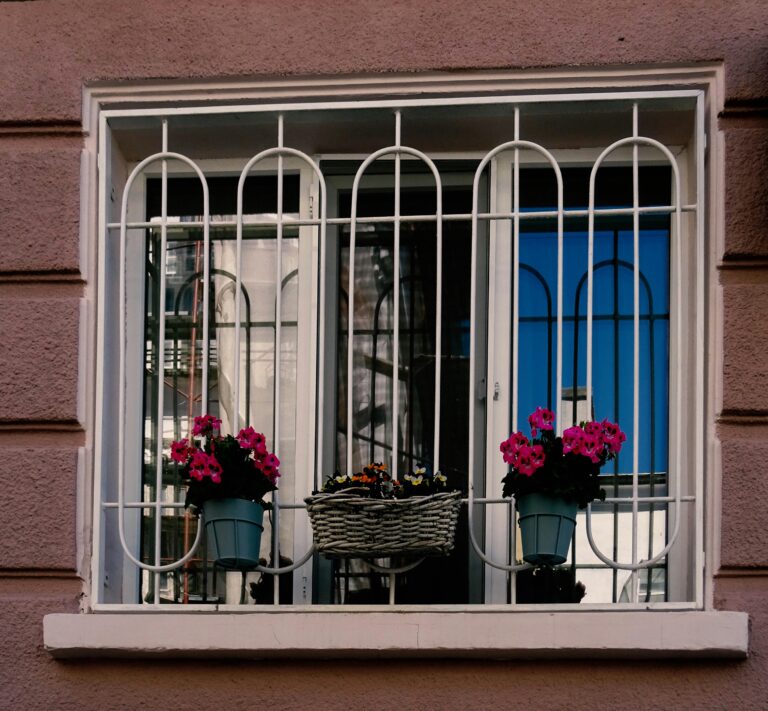 A charming window with decorative bars and vibrant flower boxes, creating a welcoming facade.