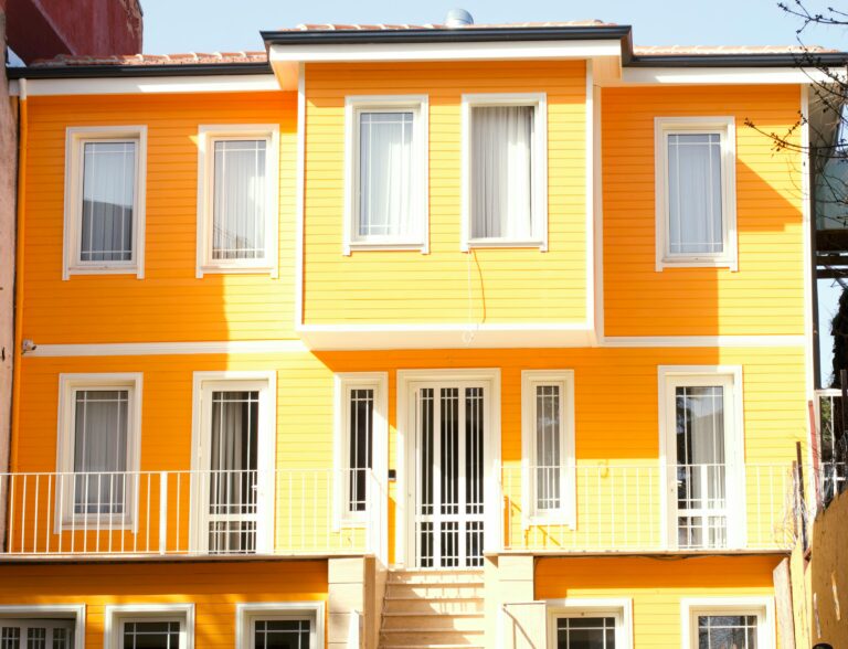 A bright yellow house exterior with white framed windows and door.